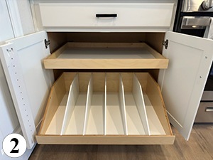 ba-2 A kitchen cabinet with two pull-out shelves; the top shelf is flat, while the bottom shelf has dividers creating six vertical compartments for organized storage. A number 2 appears in the bottom left corner.
