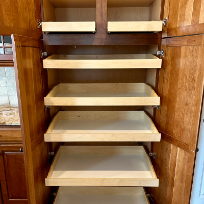 A tall wooden pantry cabinet with both doors open, revealing six pull-out shelves. The shelves are empty and extend outward, showing light wood interiors and smooth drawer slides.