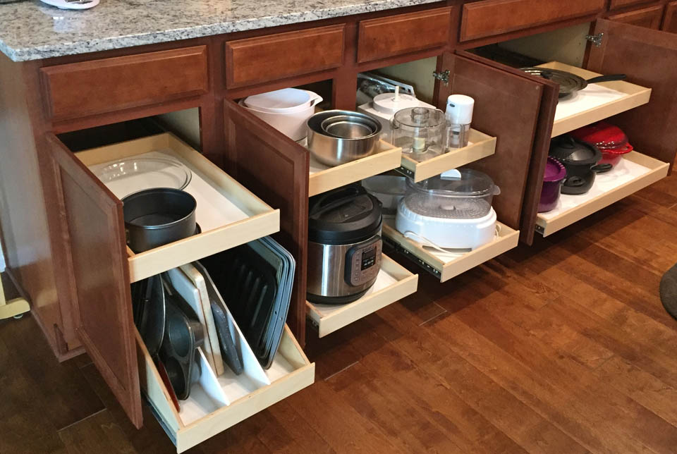 reos-product-gallery-17 Kitchen cabinets with three lower drawers open, showing organized pull-out shelves holding various cookware items, including baking sheets, pots, pans, an instant pot, mixing bowls, and kitchen appliances.